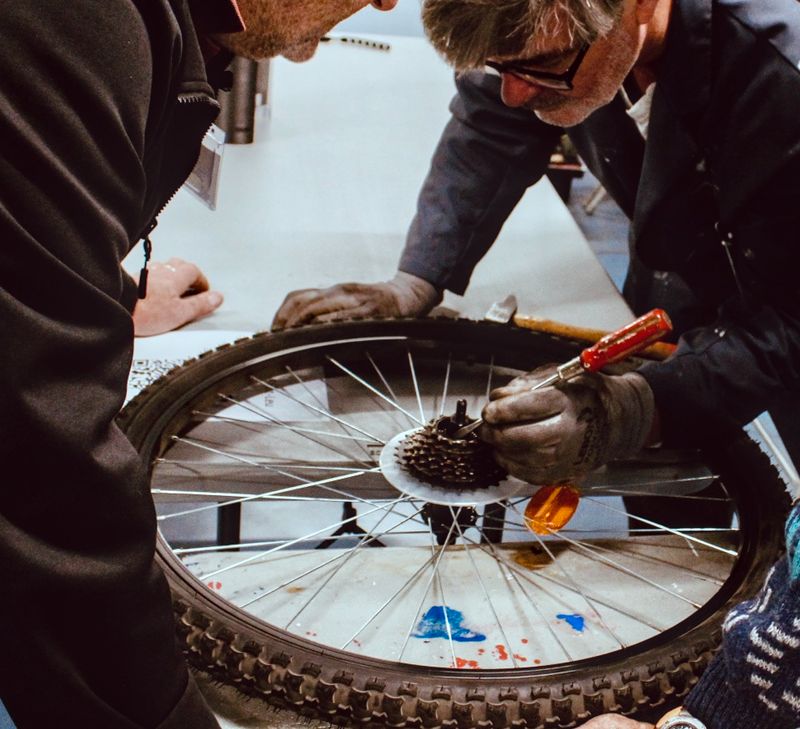 deux personnes observent une roue de vélo démontée